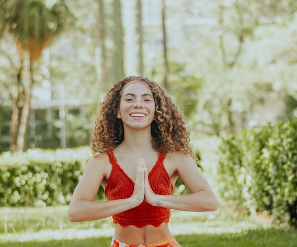 Smiling woman stretching on a yoga mat with a bright window behind her.